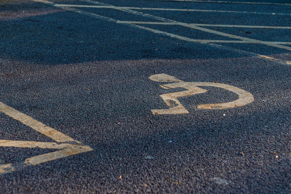 Close-up view of an asphalt parking lot surface showing a faded white number '22' within a circular boundary, with parking lines visible nearby indicating designated parking spaces. The texture of the